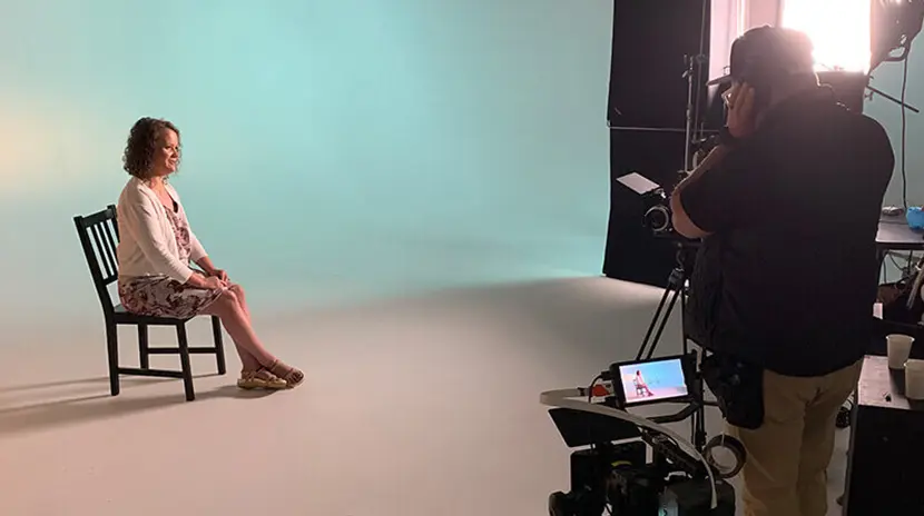 A female sitting in a chair inside a film studio.