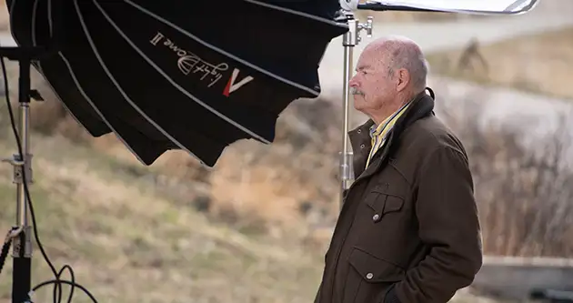 Behind the scenes of a man in front of lights and cameras.
